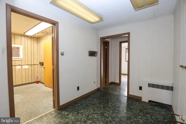 a view of a hallway with wooden floor and a bathroom