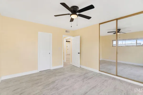a view of empty room with wooden floor and fan