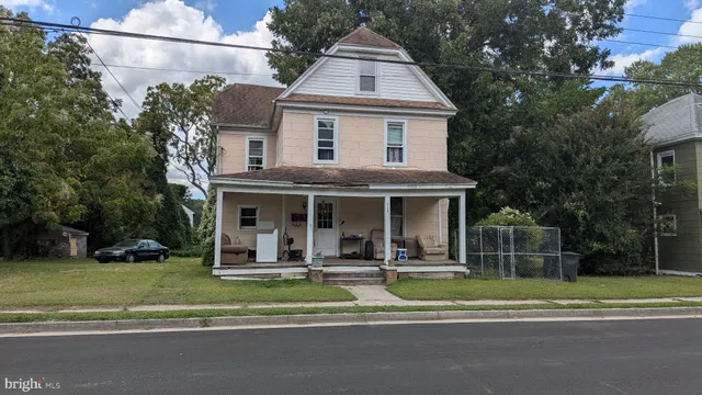 a view of a white house with a big yard and potted plants