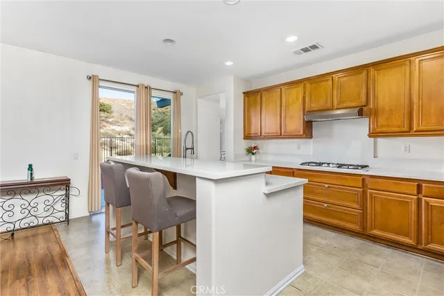 a kitchen with granite countertop wooden cabinets a sink a stove a dining table and chairs