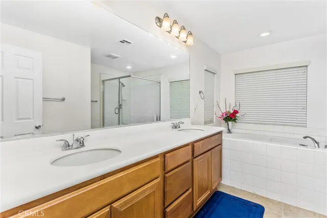 a bathroom with a granite countertop sink double vanity granite tub shower and a mirror