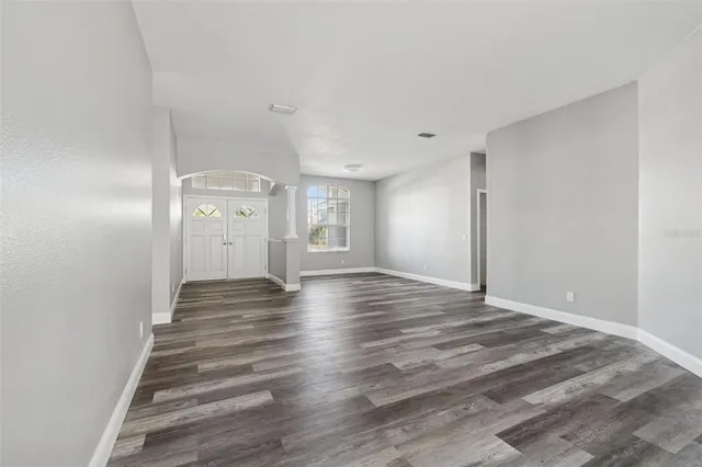 a view of an empty room with wooden floor and a window