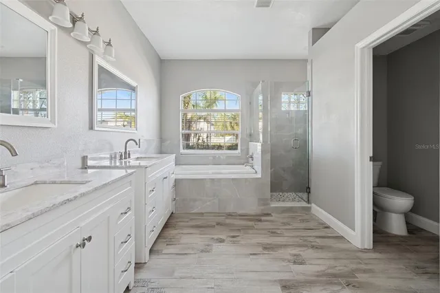 a kitchen with stainless steel appliances granite countertop a refrigerator a stove and white cabinets with wooden floor