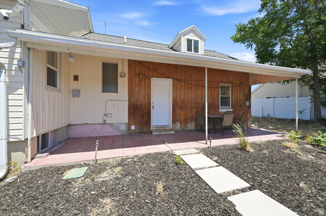 220 East Greenwood Avenue Midvale, UT 84047 - Photo 40 of 46 Covered patio with a red paver surface, wood-paneled exterior siding, and a white entry door