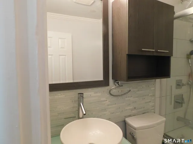 a bathroom with a toilet a sink and mirror