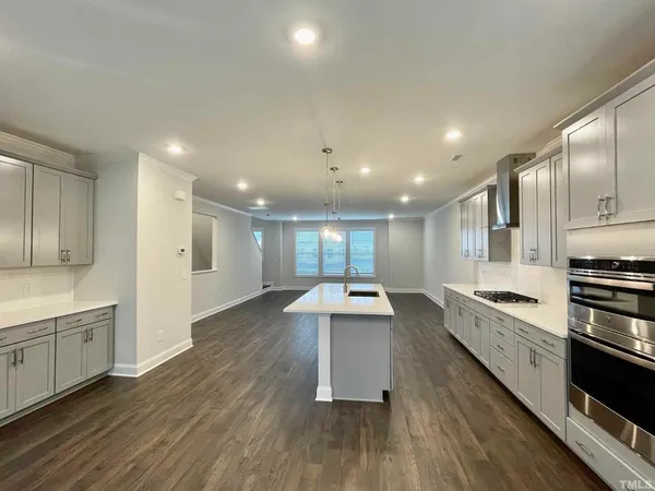 a large white kitchen with a large window a sink and stainless steel appliances