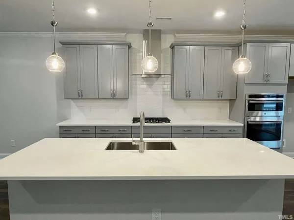 a kitchen with stainless steel appliances a white table chairs and a refrigerator