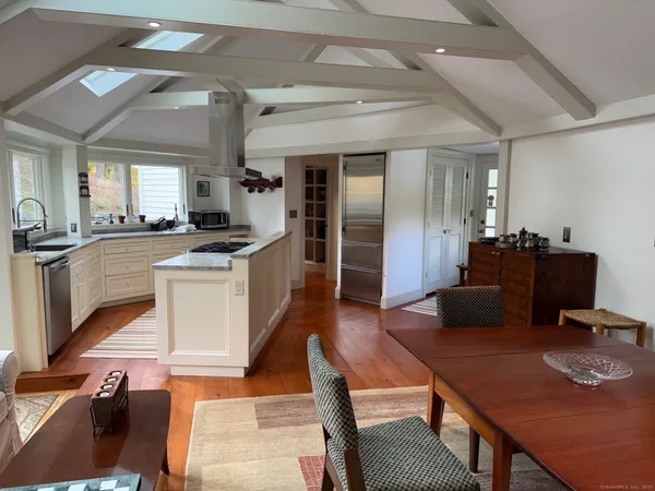 a kitchen with stainless steel appliances granite countertop a stove top oven a sink a dining table and chairs with wooden floor