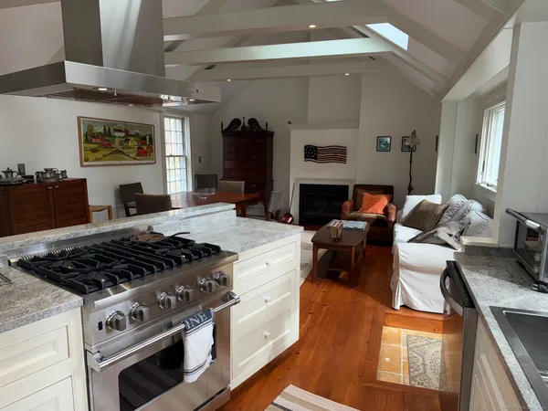 a kitchen with stainless steel appliances granite countertop a refrigerator a sink dishwasher a stove and white countertops with wooden floor