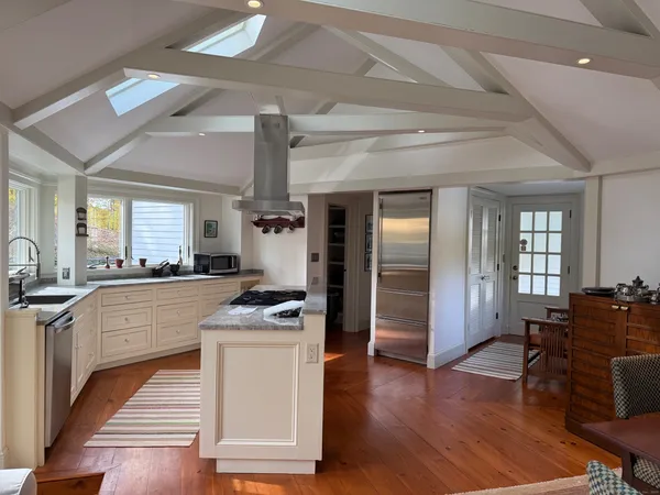a living room with furniture a rug kitchen view and a large window