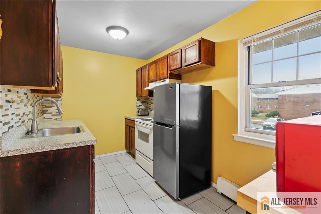 132 The Orchard, Unit L Cranbury, NJ 08512 - Photo 5 of 10 a kitchen with stainless steel appliances granite countertop a refrigerator a stove and a sink