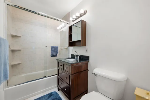 a bathroom with a granite countertop sink toilet a mirror and shower