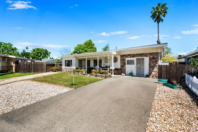 a front view of a house with a yard and potted plants
