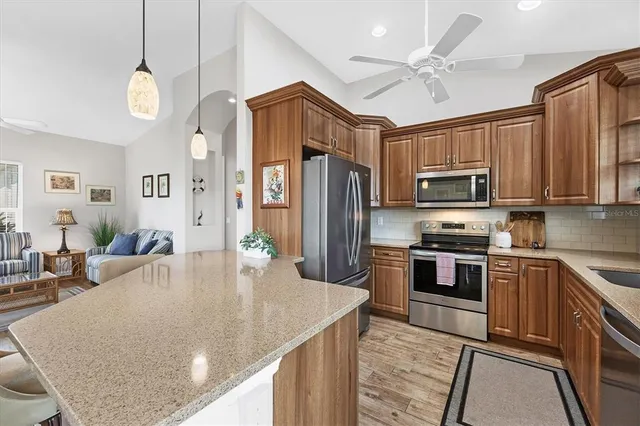 a kitchen with stainless steel appliances granite countertop a sink a stove top oven a refrigerator with island and chairs