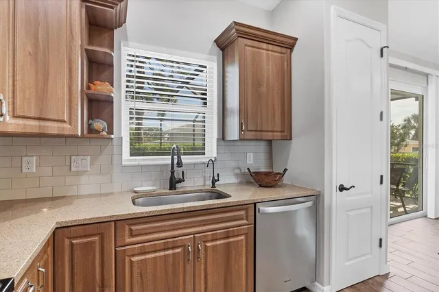a kitchen with stainless steel appliances granite countertop white cabinets and a window