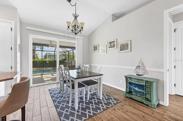 a dining room with wooden floor a chandelier a wooden table and chairs