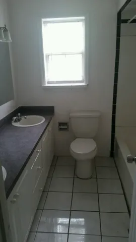 a bathroom with a granite countertop toilet a sink and a window