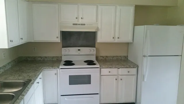 a kitchen with granite countertop white cabinets and white appliances