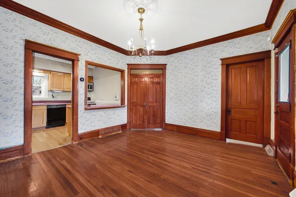 a view of an empty room with window and wooden floor