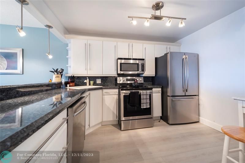 a kitchen with kitchen island granite countertop stainless steel appliances and refrigerator