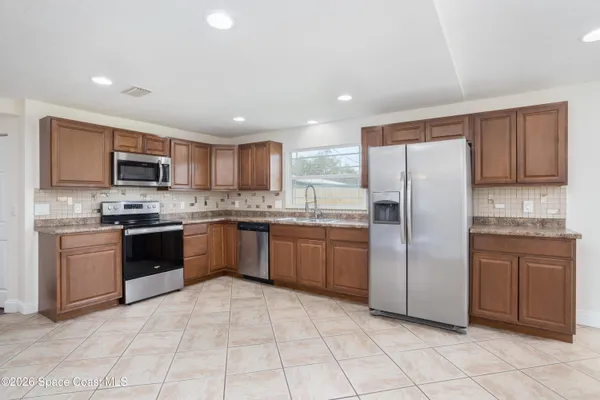 a large kitchen with cabinets a sink and stainless steel appliances