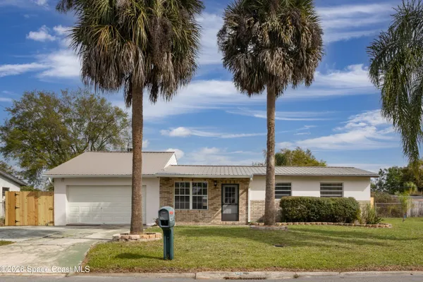 front view of a house with a yard and palm trees