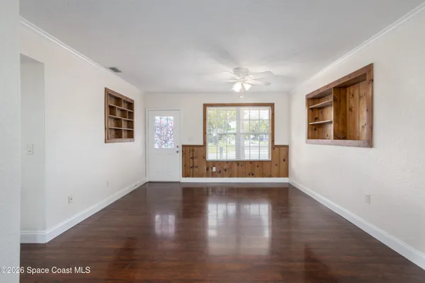 a view of an empty room with wooden floor and a window