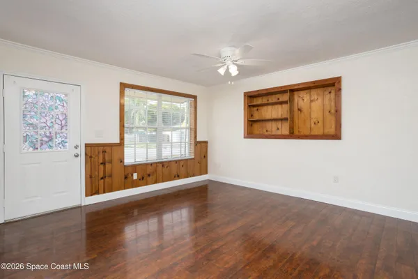 an empty room with wooden floor and windows