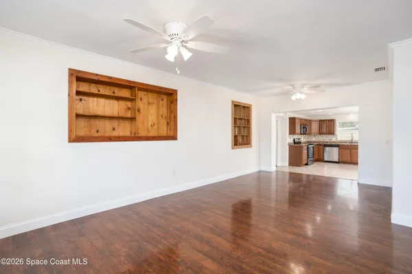 a view of an empty room with wooden floor and a window