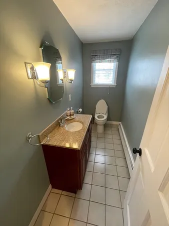 a bathroom with a granite countertop sink a toilet a mirror and window