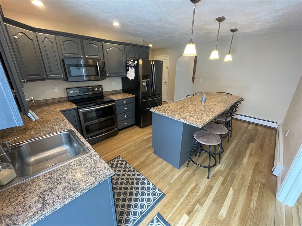 4 Indiana Avenue, Unit 4 Woburn, MA 01801 - Photo 9 of 26 a kitchen with stainless steel appliances kitchen island granite countertop a stove a sink and a microwave