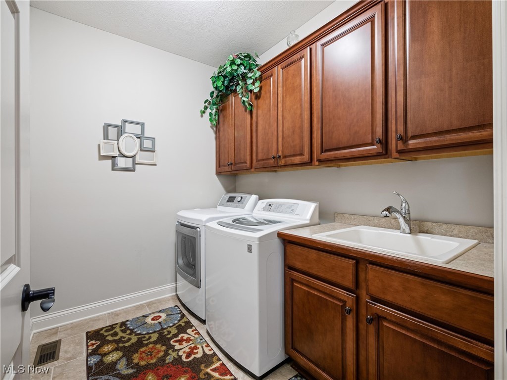 5349 Slater Ridge Westerville, OH 43082 - Photo 8 of 50 Washroom with washer and clothes dryer, light tile patterned floors, cabinet space, and a textured ceiling