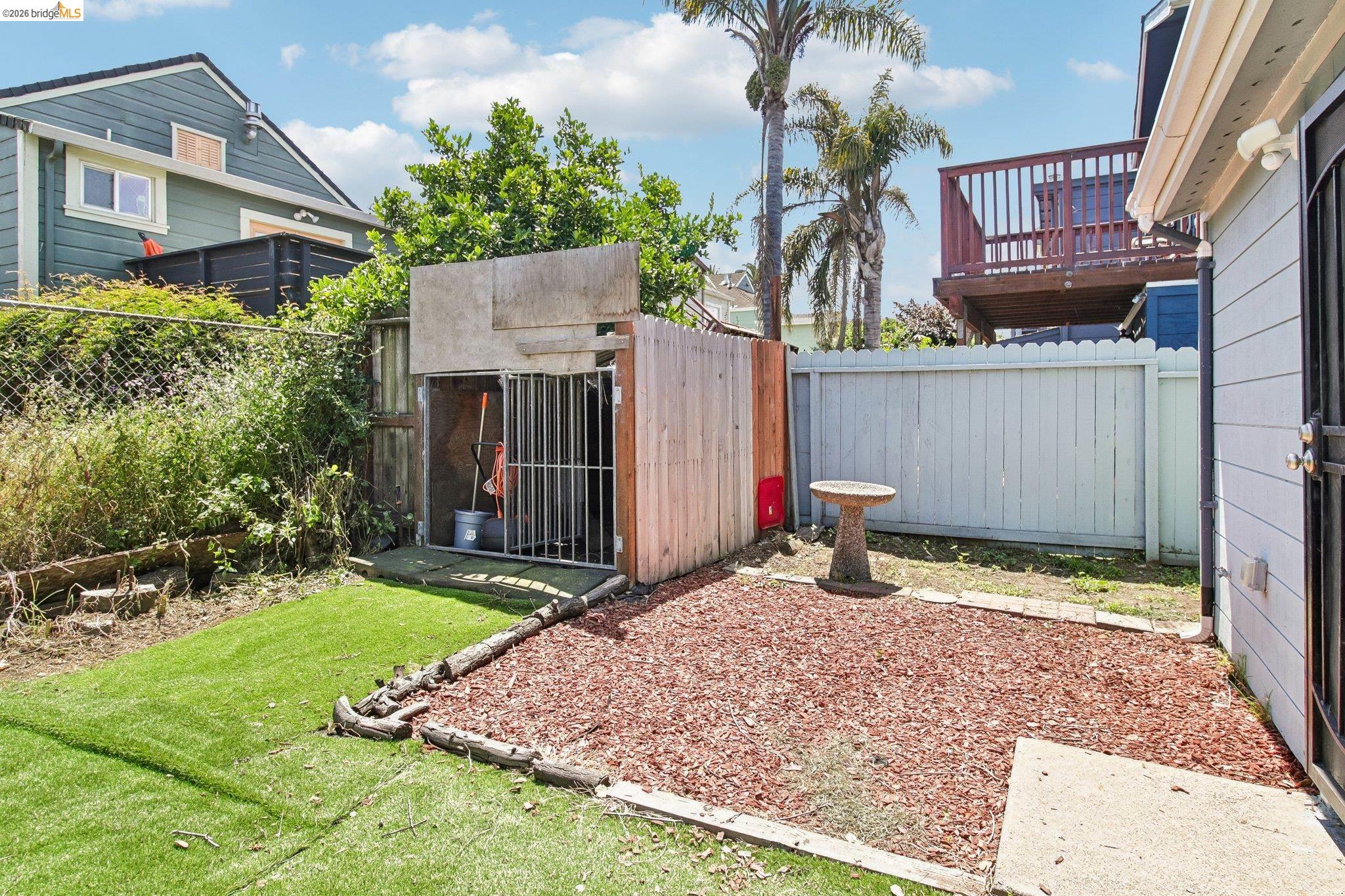 874 Pine Street Oakland, CA 94607 - Photo 27 of 39 Compact outdoor area featuring a storage shed with metal grating, an artificial turf section, and a bark-mulch ground cover