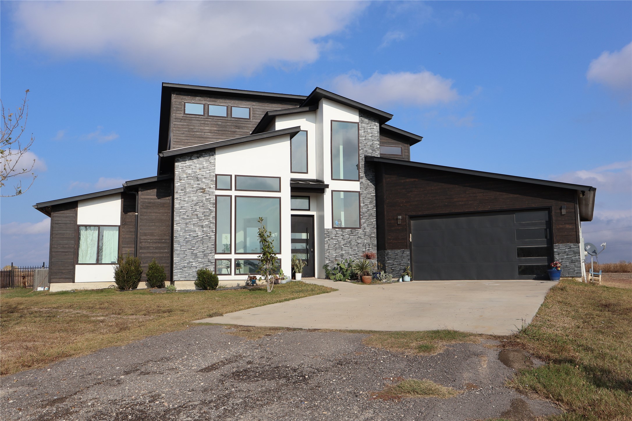 17216 Lund - Carlson Road Elgin, TX 78621 - Photo 16 of 17 Contemporary home with stone siding, concrete driveway, a front yard, and an attached garage