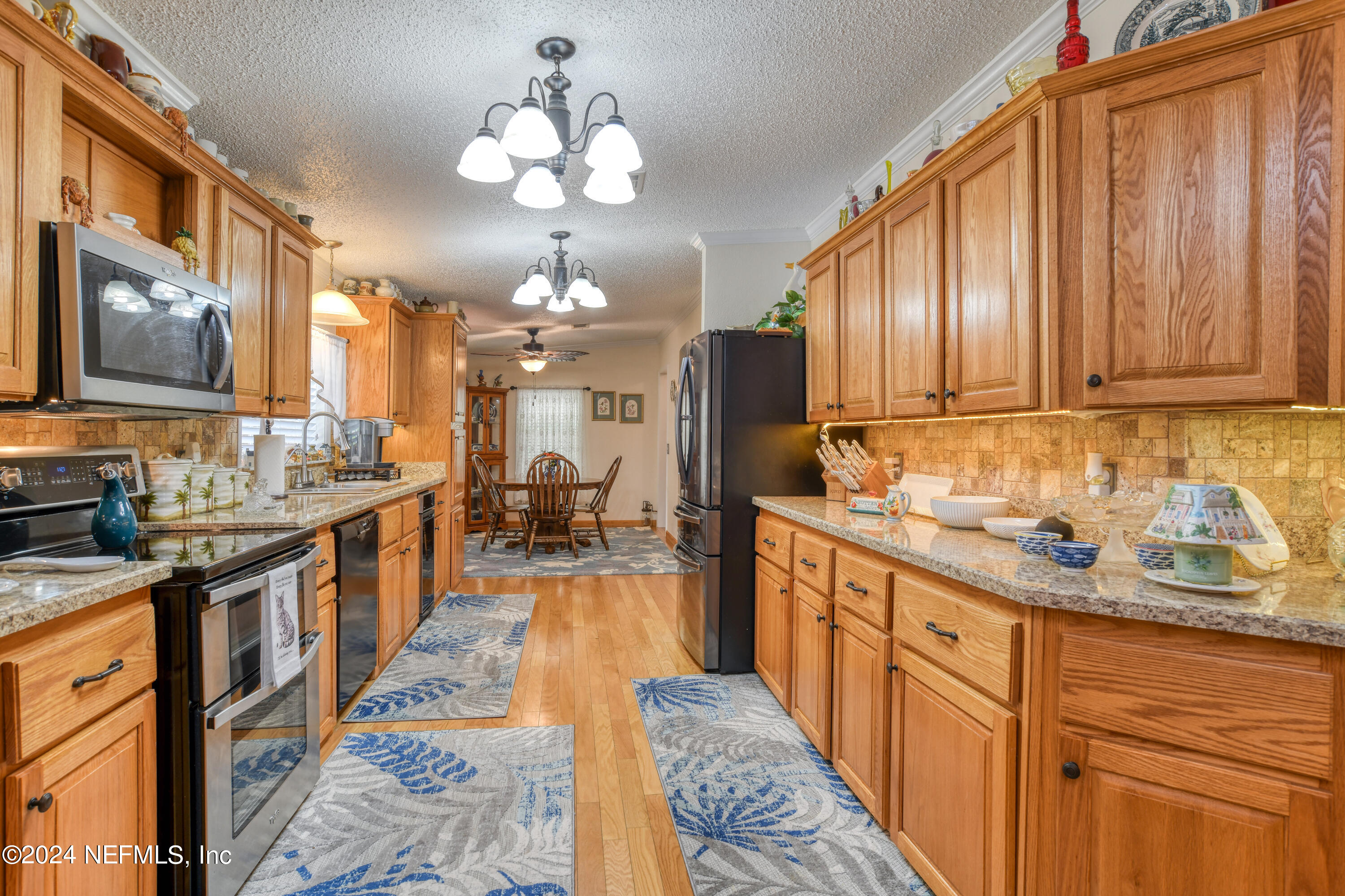 131 Sunset Drive Crescent City, FL 32112 - Photo 6 of 33 a large kitchen with stainless steel appliances granite countertop a stove top oven a sink dishwasher and cabinets with wooden floor