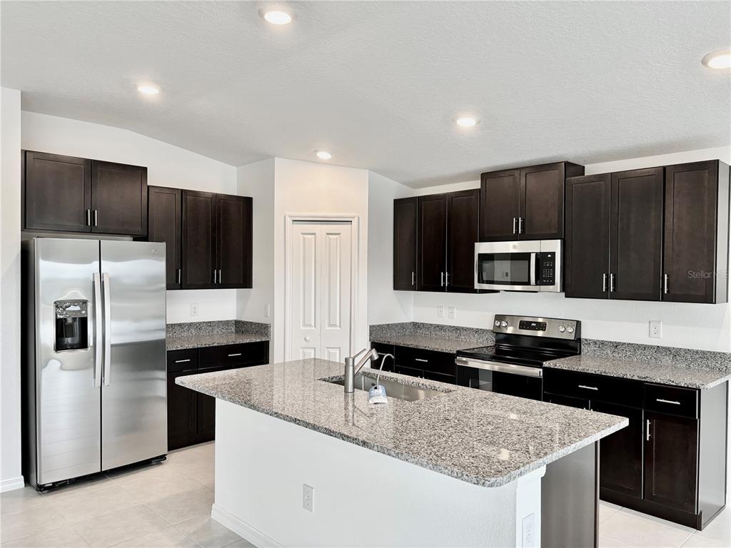 11237 Linden Depot Road San Antonio, FL 33576 - Photo 5 of 31 a kitchen with kitchen island granite countertop stainless steel appliances a sink stove and refrigerator