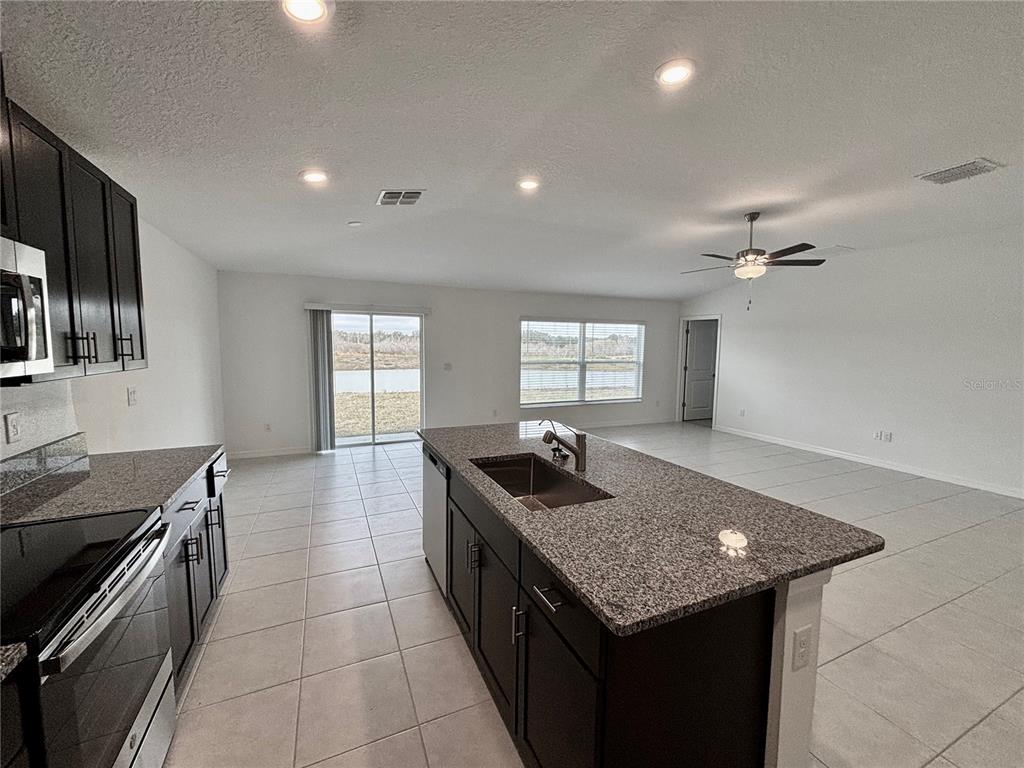11237 Linden Depot Road San Antonio, FL 33576 - Photo 6 of 31 a kitchen with granite countertop kitchen island stainless steel appliances a sink stove and cabinets