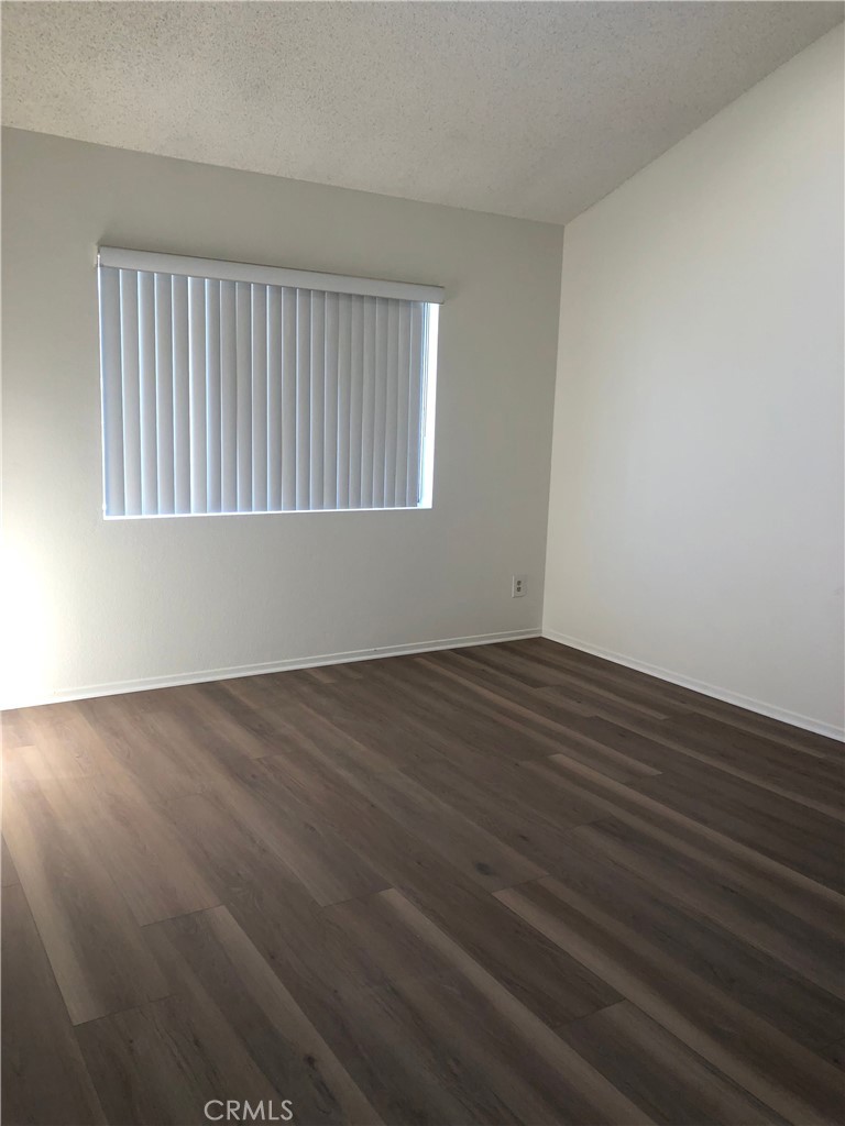 16621 Dolores Lane, Unit B Huntington Beach, CA 92649 - Photo 14 of 22 a view of an empty room with wooden floor and a window
