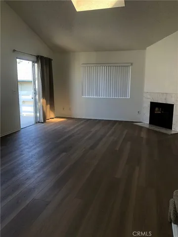 an empty room with wooden floor fireplace and windows
