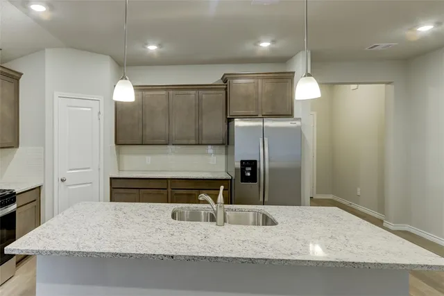 a kitchen with kitchen island a sink and refrigerator