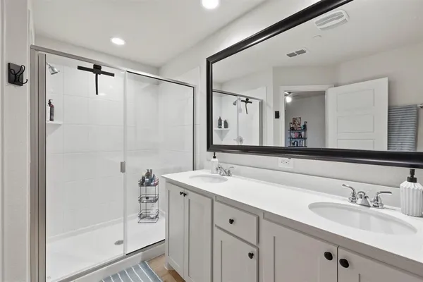 a bathroom with a double vanity sink mirror and shower