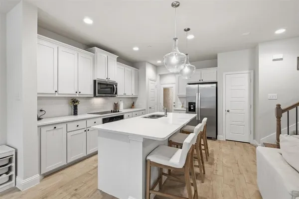 a kitchen with stainless steel appliances a stove refrigerator sink cabinets dining table and chairs