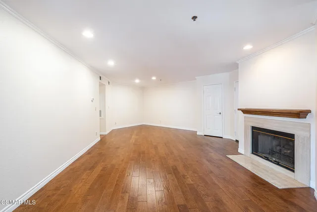 a view of empty room with wooden floor and fireplace