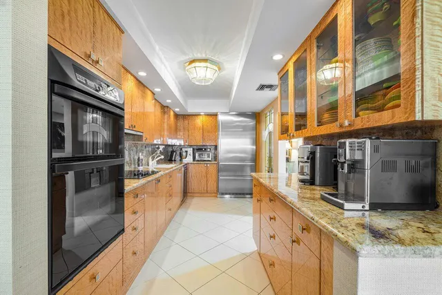 a large kitchen with stainless steel appliances a large counter top a stove and a refrigerator