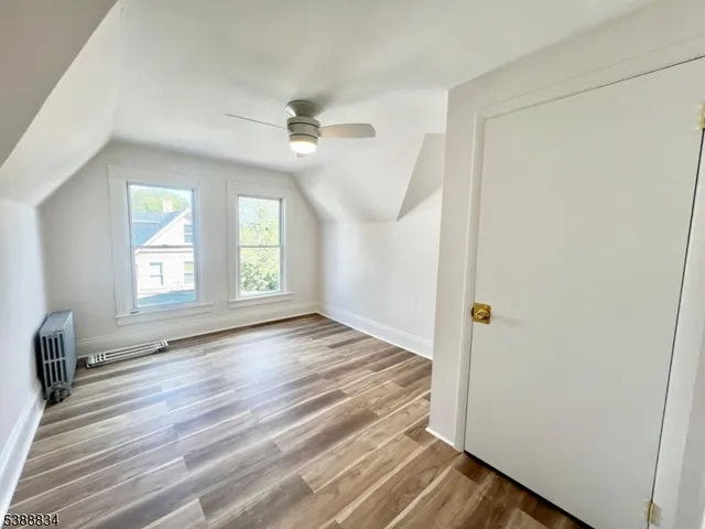 an empty room with wooden floor fan and windows