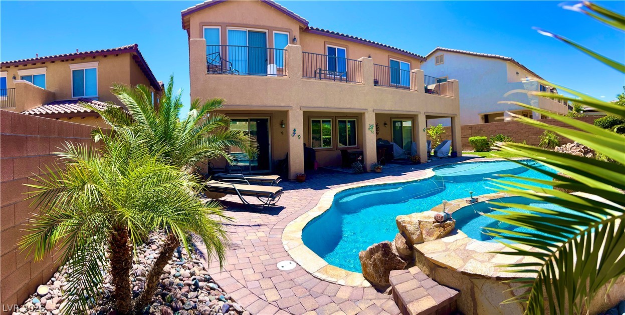 9724 University Ridge Avenue Las Vegas, NV 89149 - Photo 30 of 61 An inviting backyard oasis awaits with a sparkling pool and elevated spa, framed by mature palms and elegant paver patio.