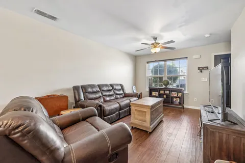 a living room with furniture ceiling fan and a wooden floor