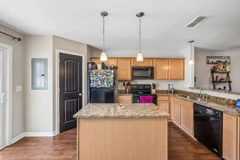 a kitchen with granite countertop kitchen island stainless steel appliances a refrigerator sink stove microwave and cabinets
