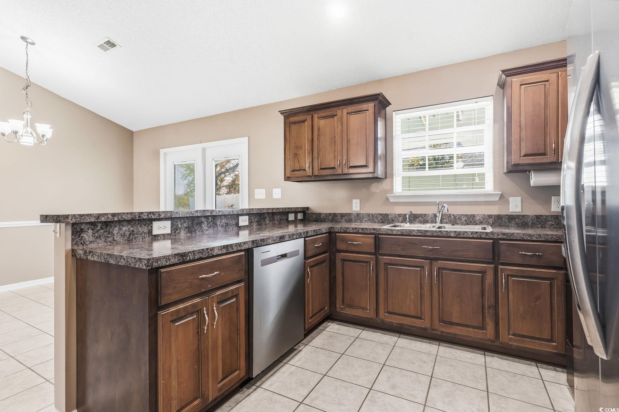 1007 Green Fir Loop Conway, SC 29527 - Photo 13 of 38 Kitchen with dark countertops, light tile patterned flooring, a peninsula, appliances with stainless steel finishes, and dark brown cabinets