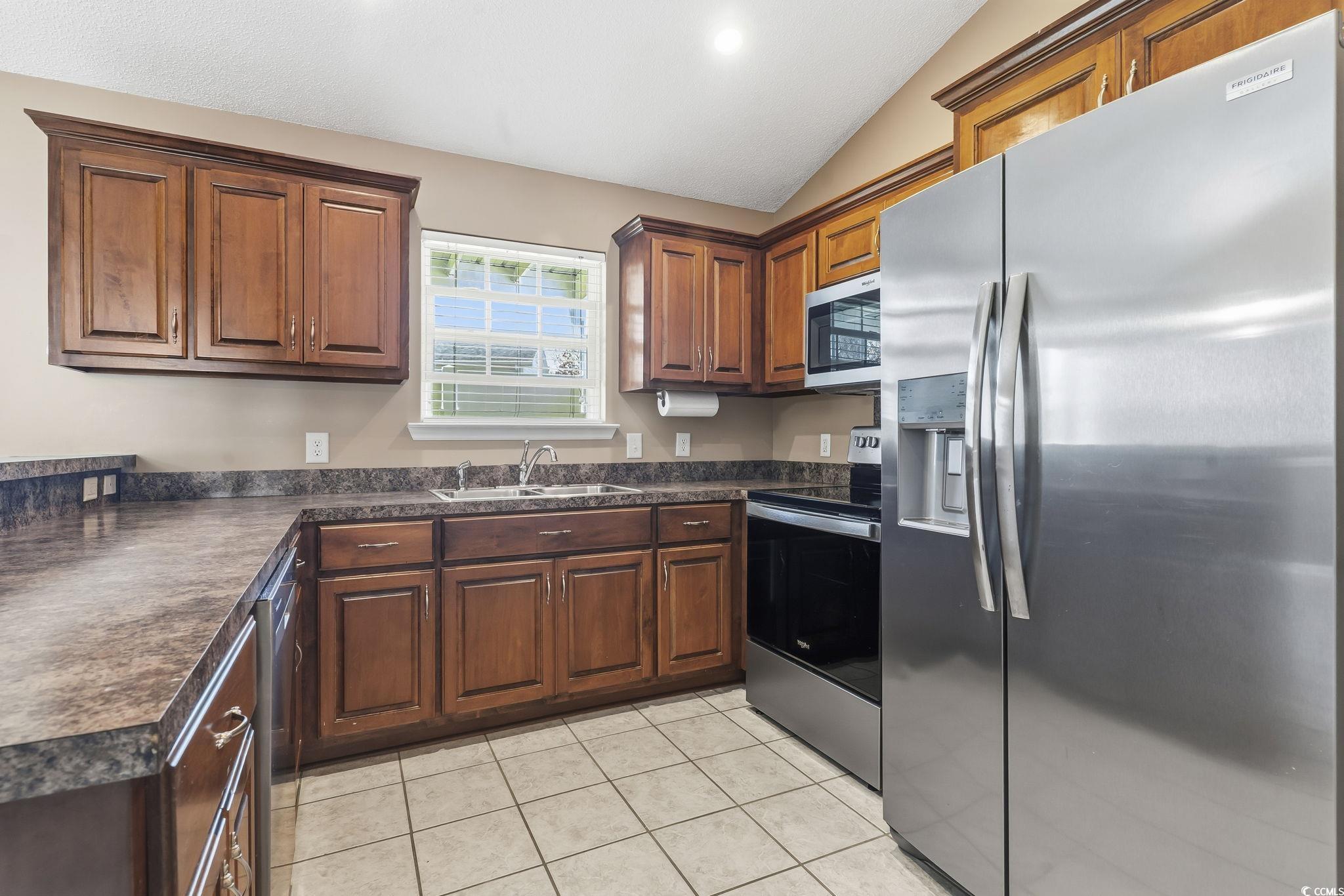 1007 Green Fir Loop Conway, SC 29527 - Photo 14 of 38 Kitchen with appliances with stainless steel finishes, dark countertops, vaulted ceiling, light tile patterned floors, and recessed lighting